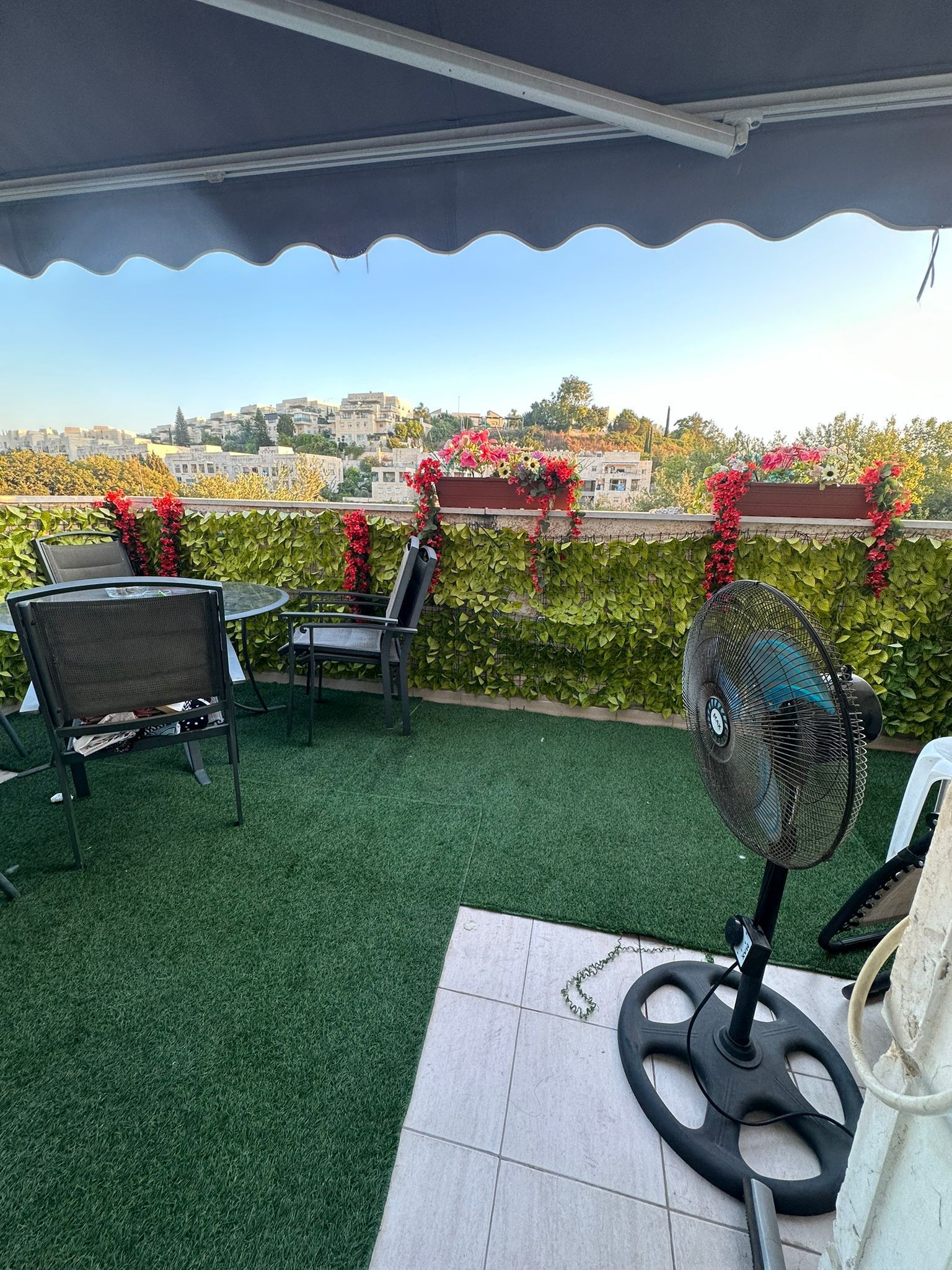 מאוורר יושב על פטיו ליד שולחן וכיסאות.