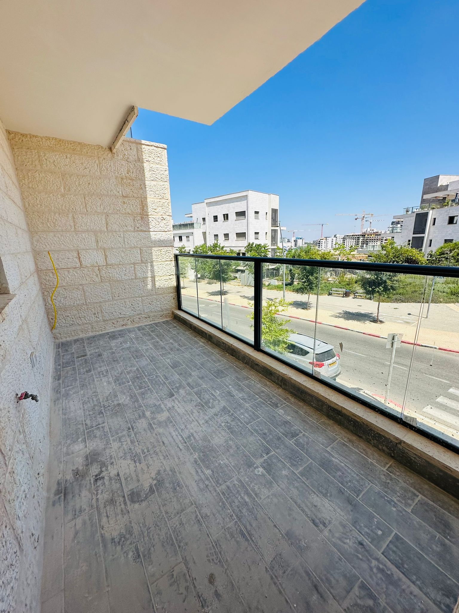 מרפסת ריקה עם מעקה זכוכית ונוף לעיר.