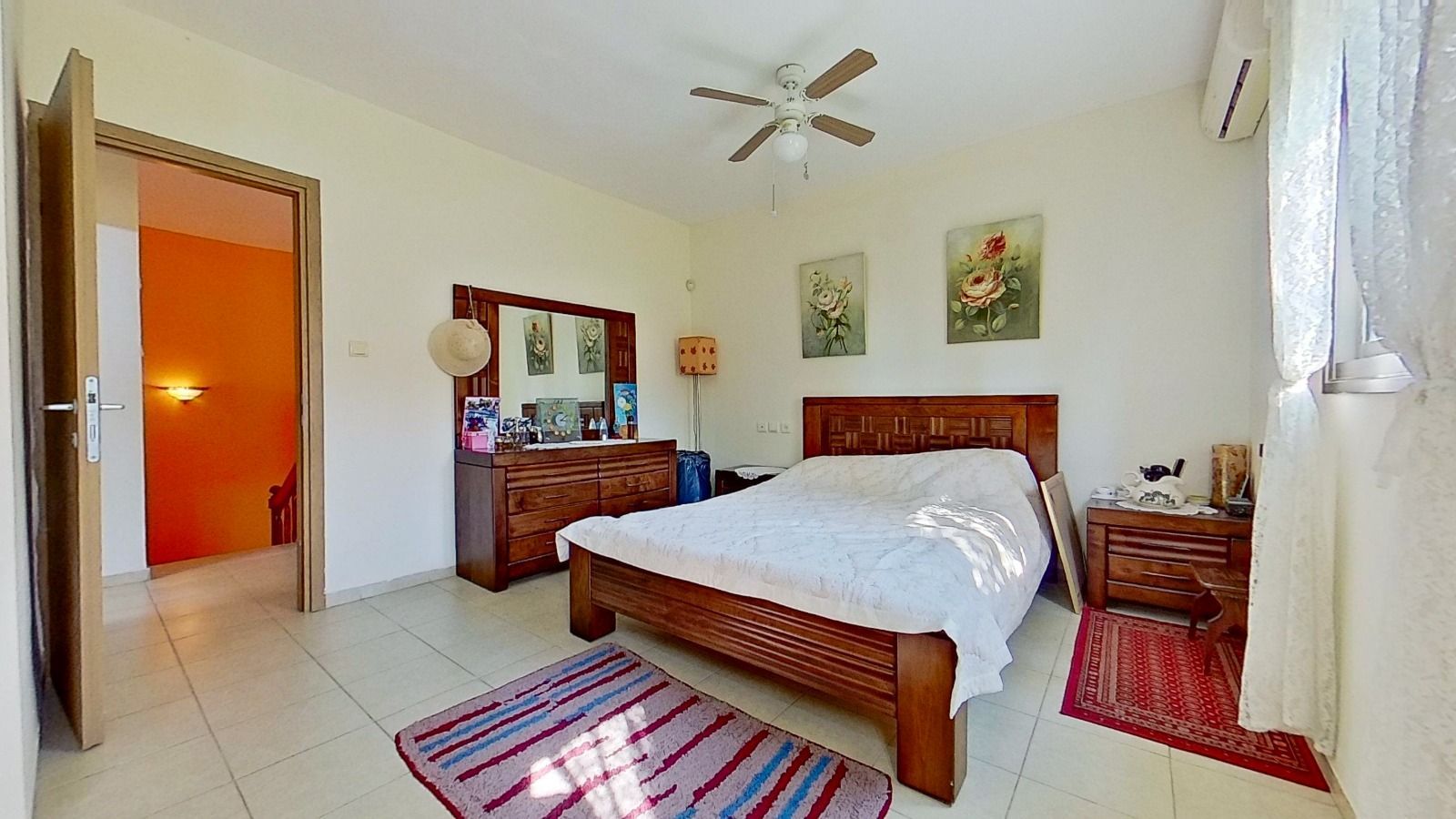 חדר שינה עם מיטה, שידת לילה, מראה ומאוורר תקרה.