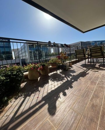 מרפסת עם עציצים וכיסאות ביום שמש