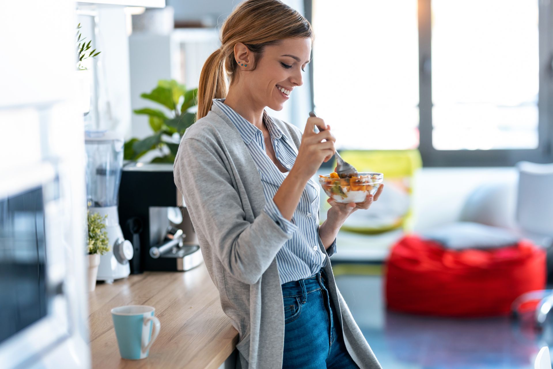 a woman is eating a salad from a bowl in a kitchen .