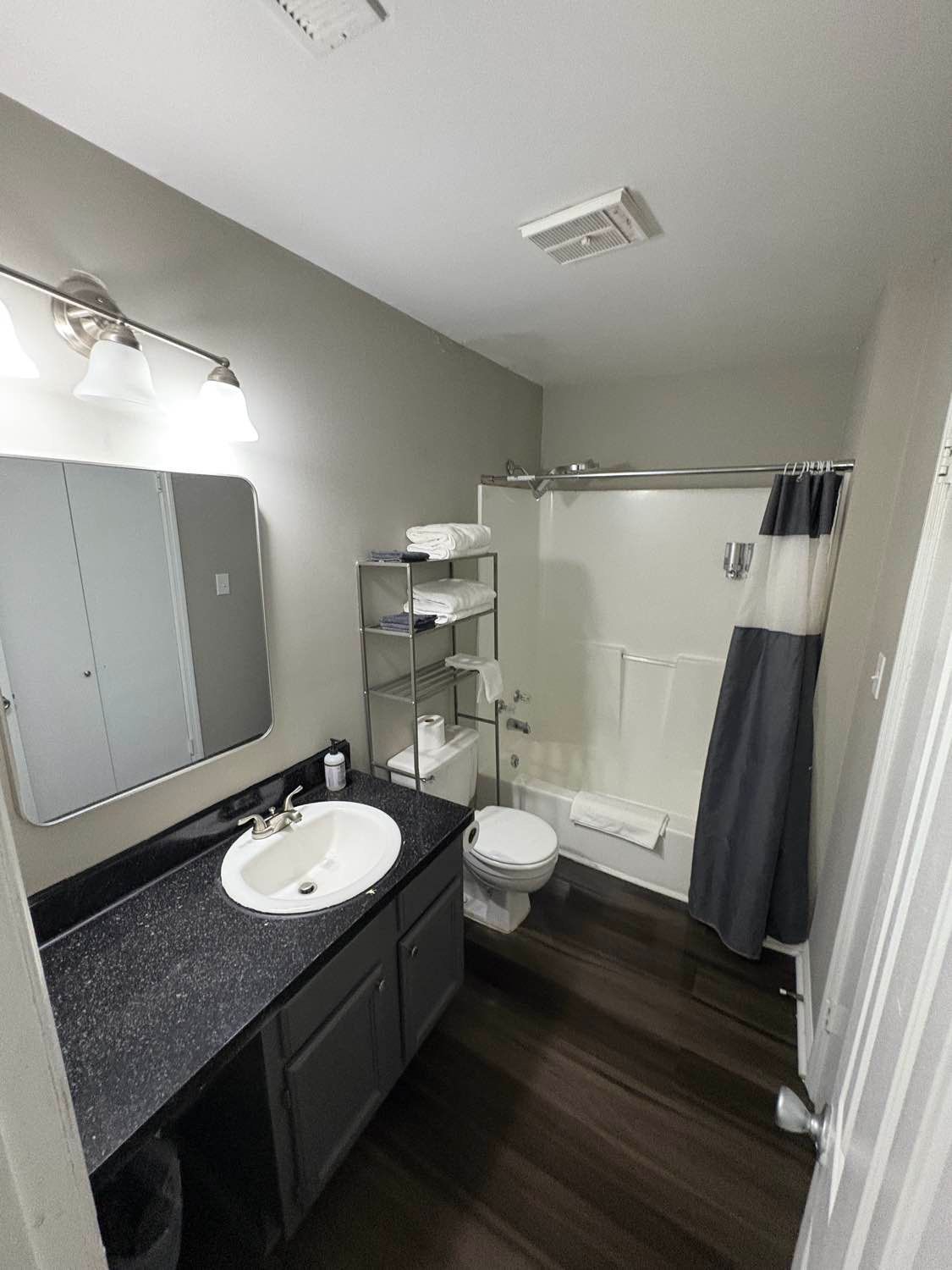 Bathroom with dark floors, gray walls, white fixtures, and a dark countertop.