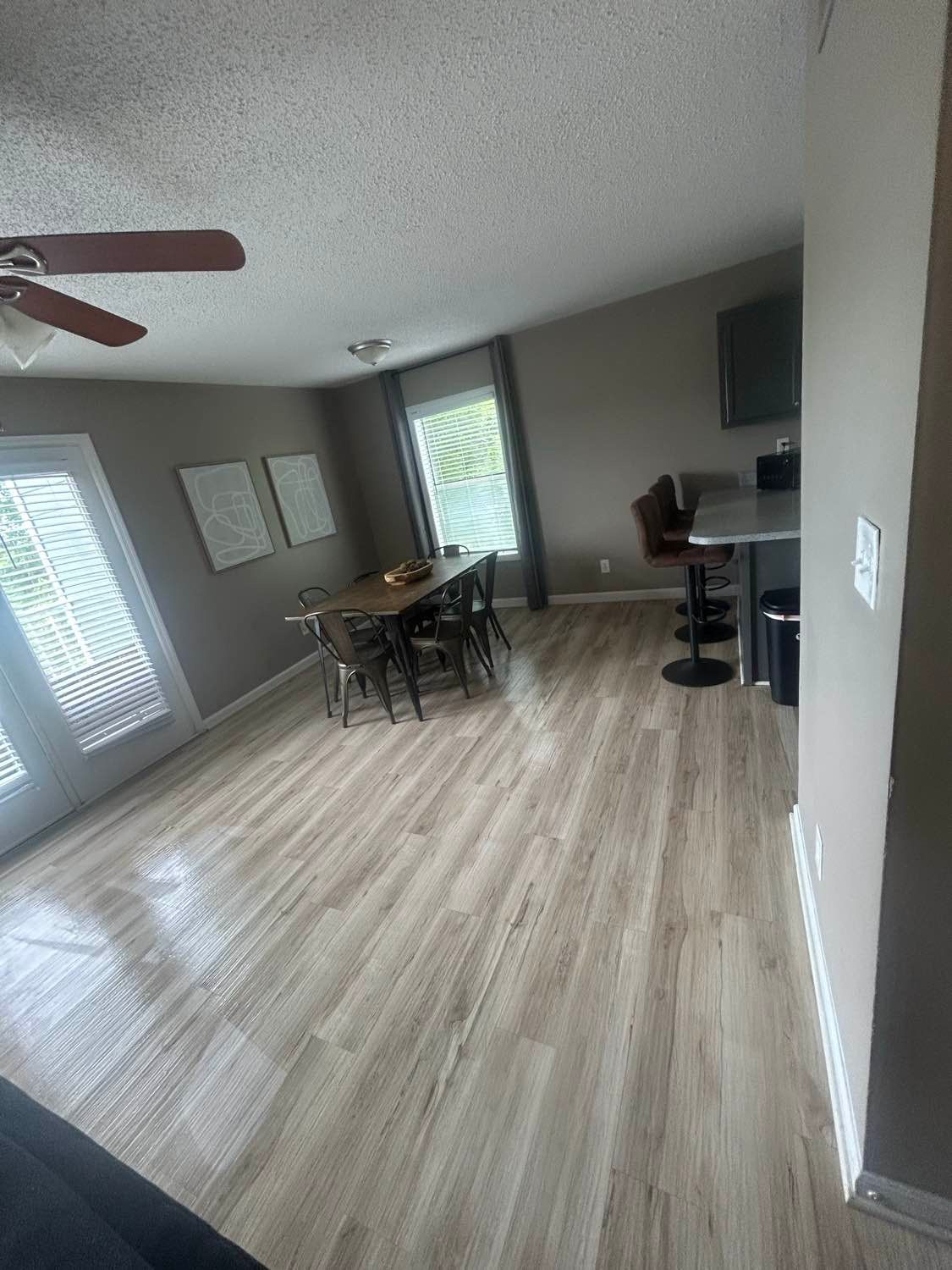 Dining room with wood flooring, table and chairs, and a bar with stools.