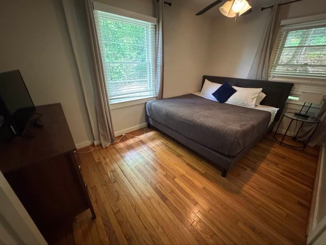 Bedroom with a bed, dresser, window, and hardwood floor.