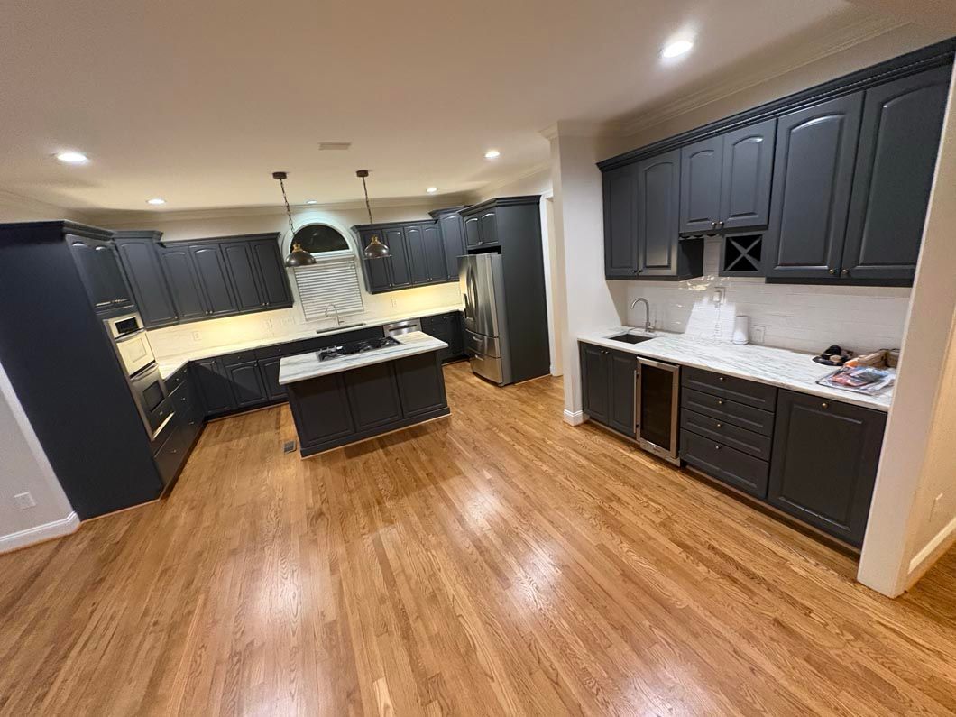 Two people in red coveralls unload a van near a house, vacuum cleaner visible.
