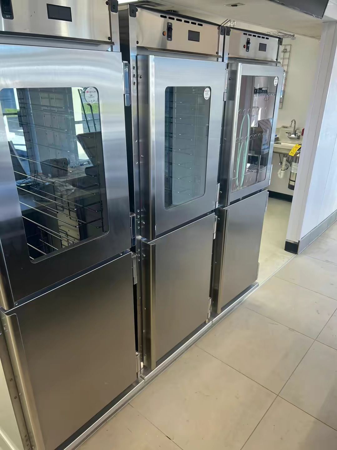 A row of three stainless steel commercial ovens in a kitchen setting.