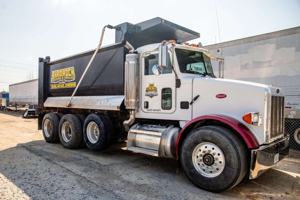 A white dump truck is parked on the side of the road.