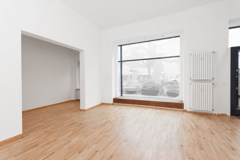 an empty room with wooden floors and a large window