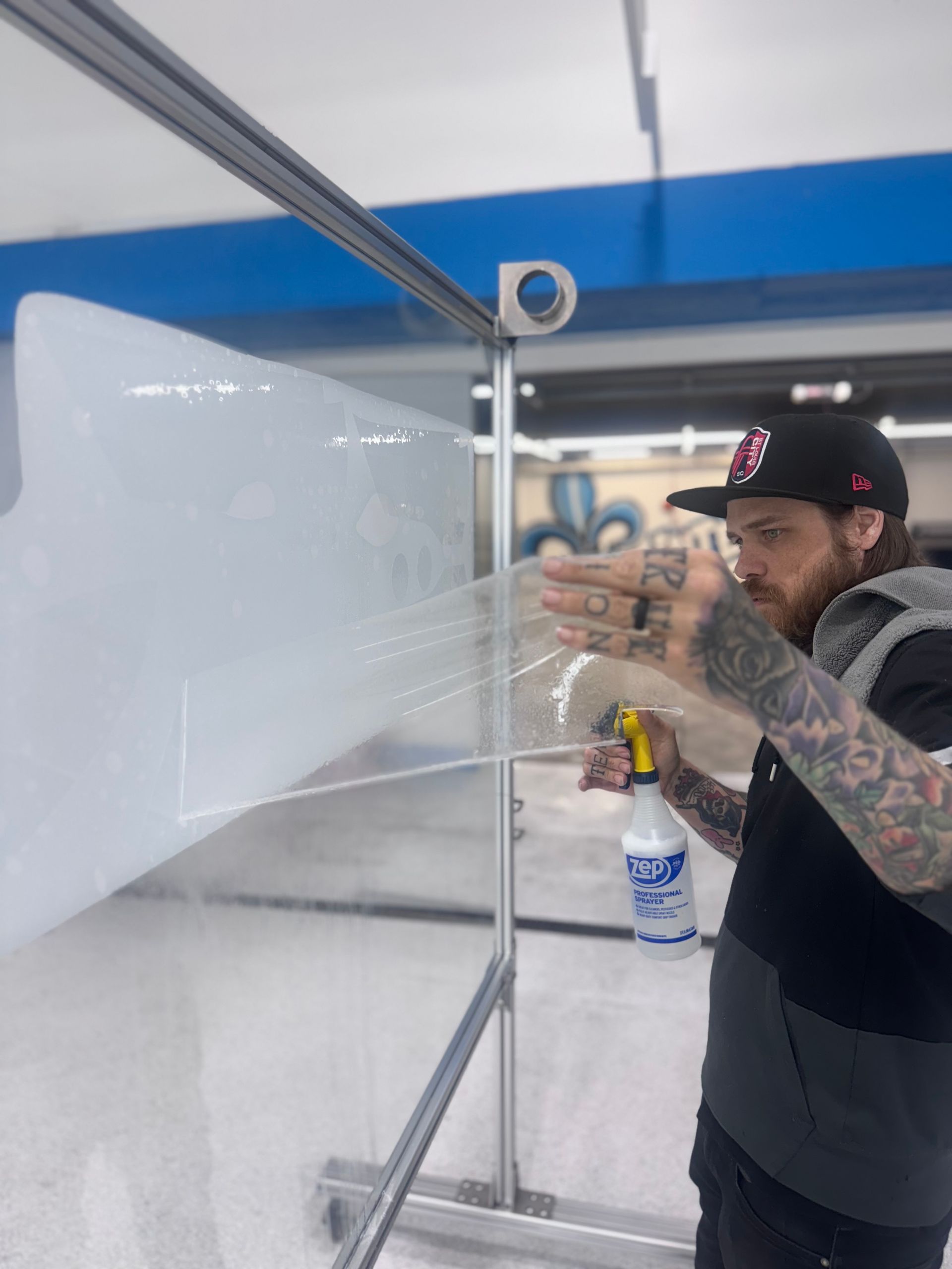 A man is applying a protective film to the hood of a car.
