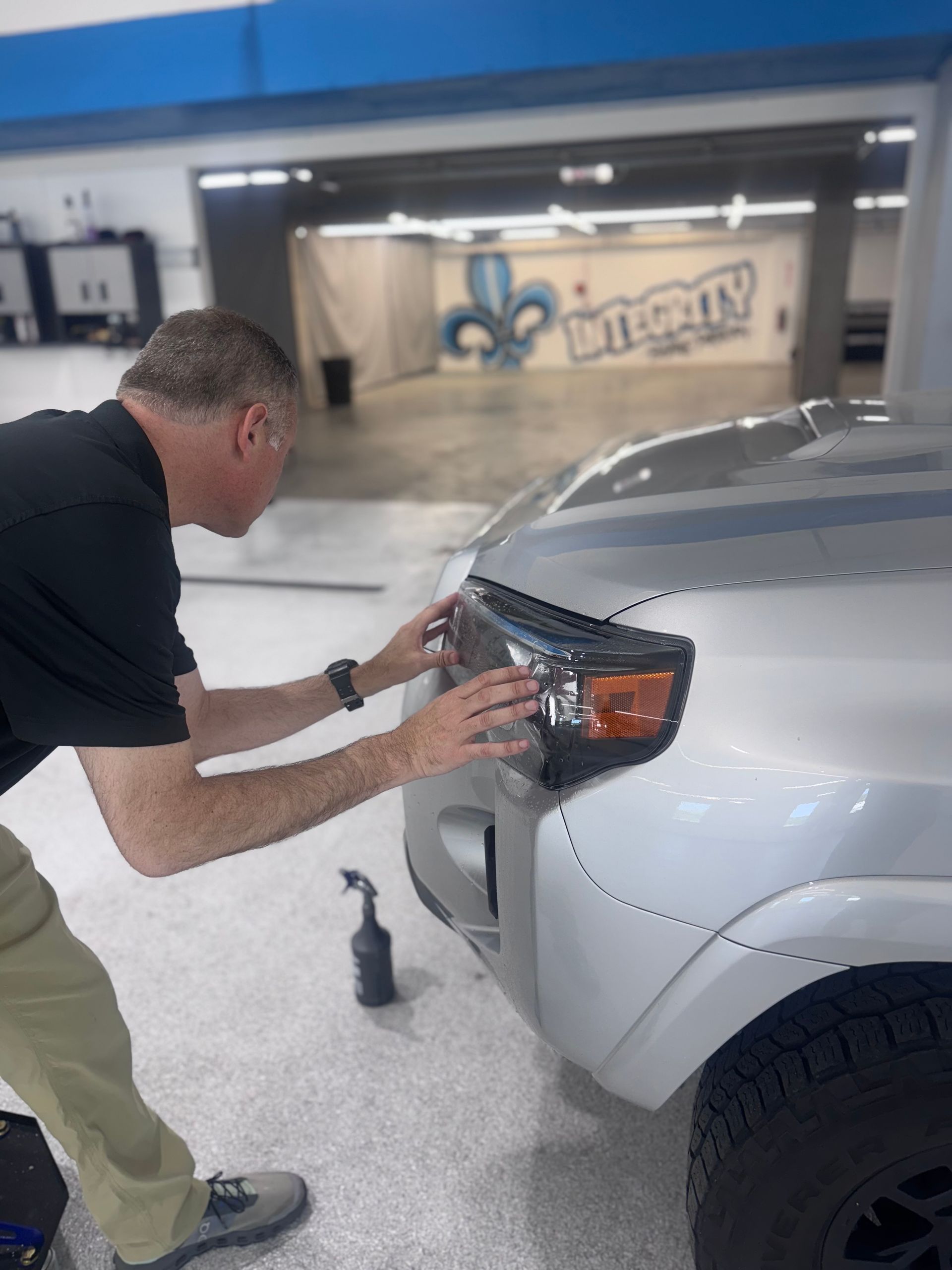 A woman is applying a protective film to the side of a car.