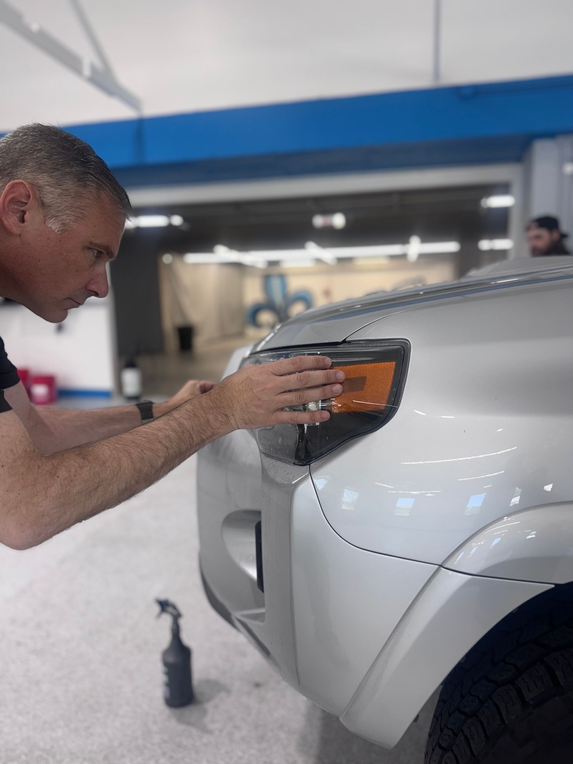 A person is applying a protective film to a car.