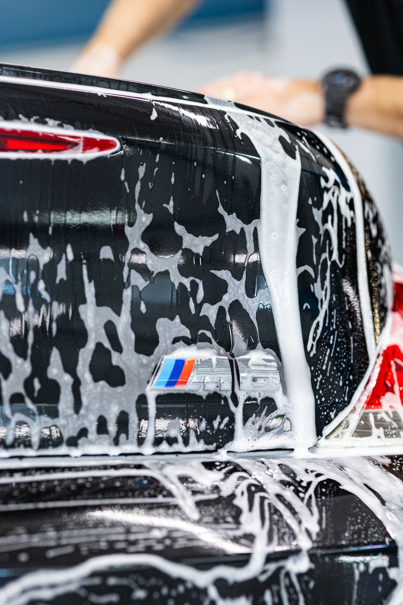Black car trunk with foam being washed, BMW logo visible.
