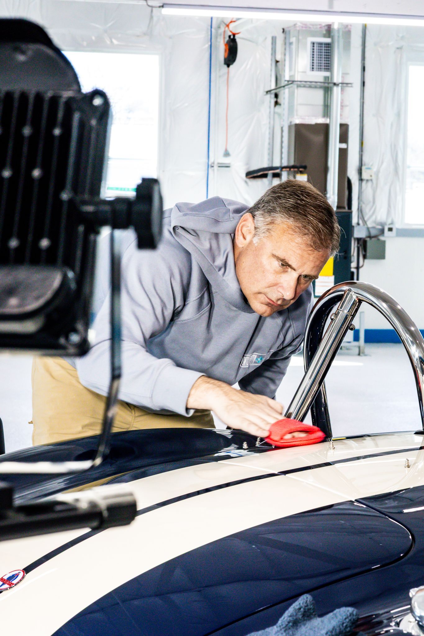 A person is cleaning the hood of a car in a garage.