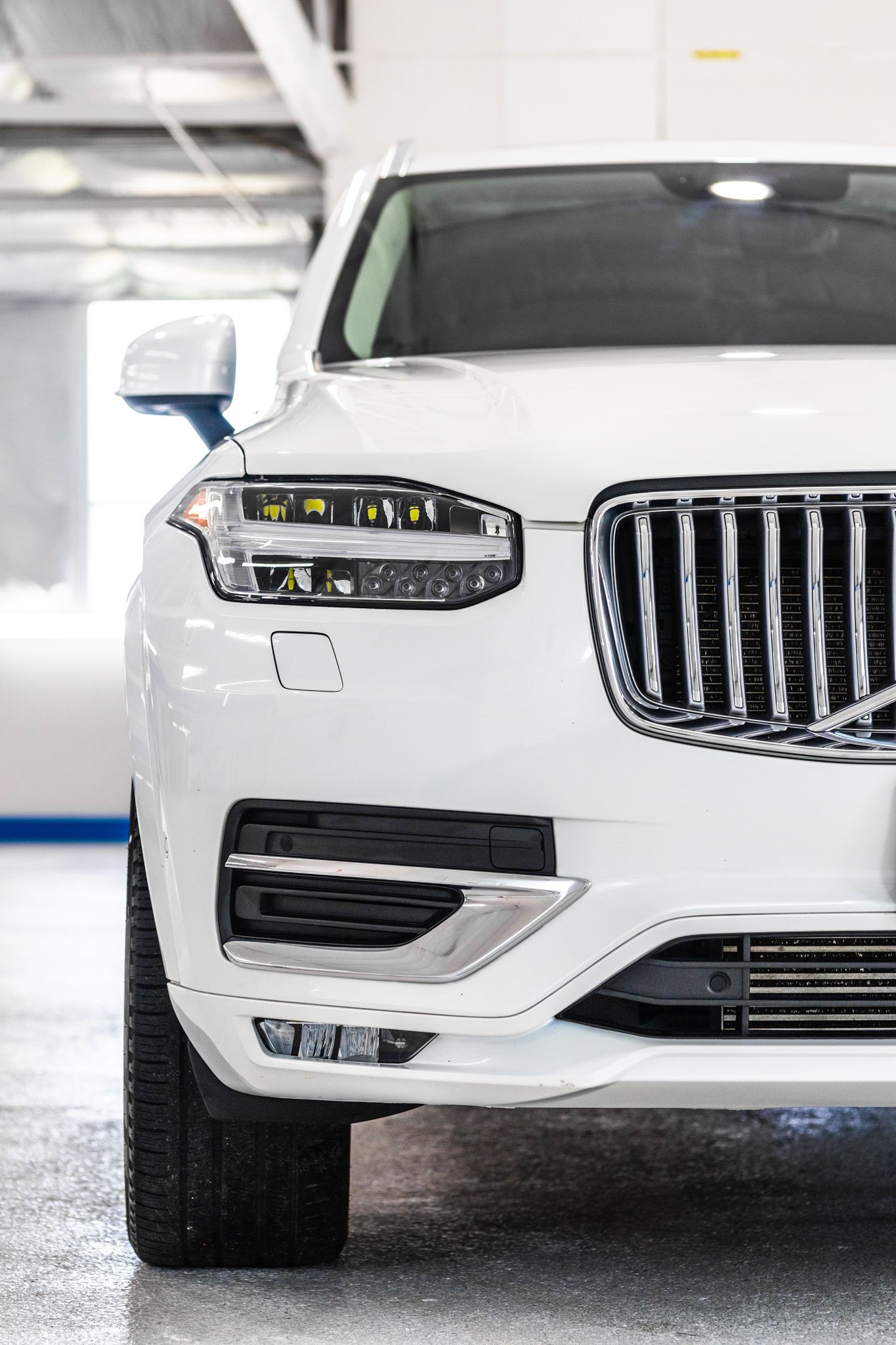 A black volvo xc90 is parked in a garage.