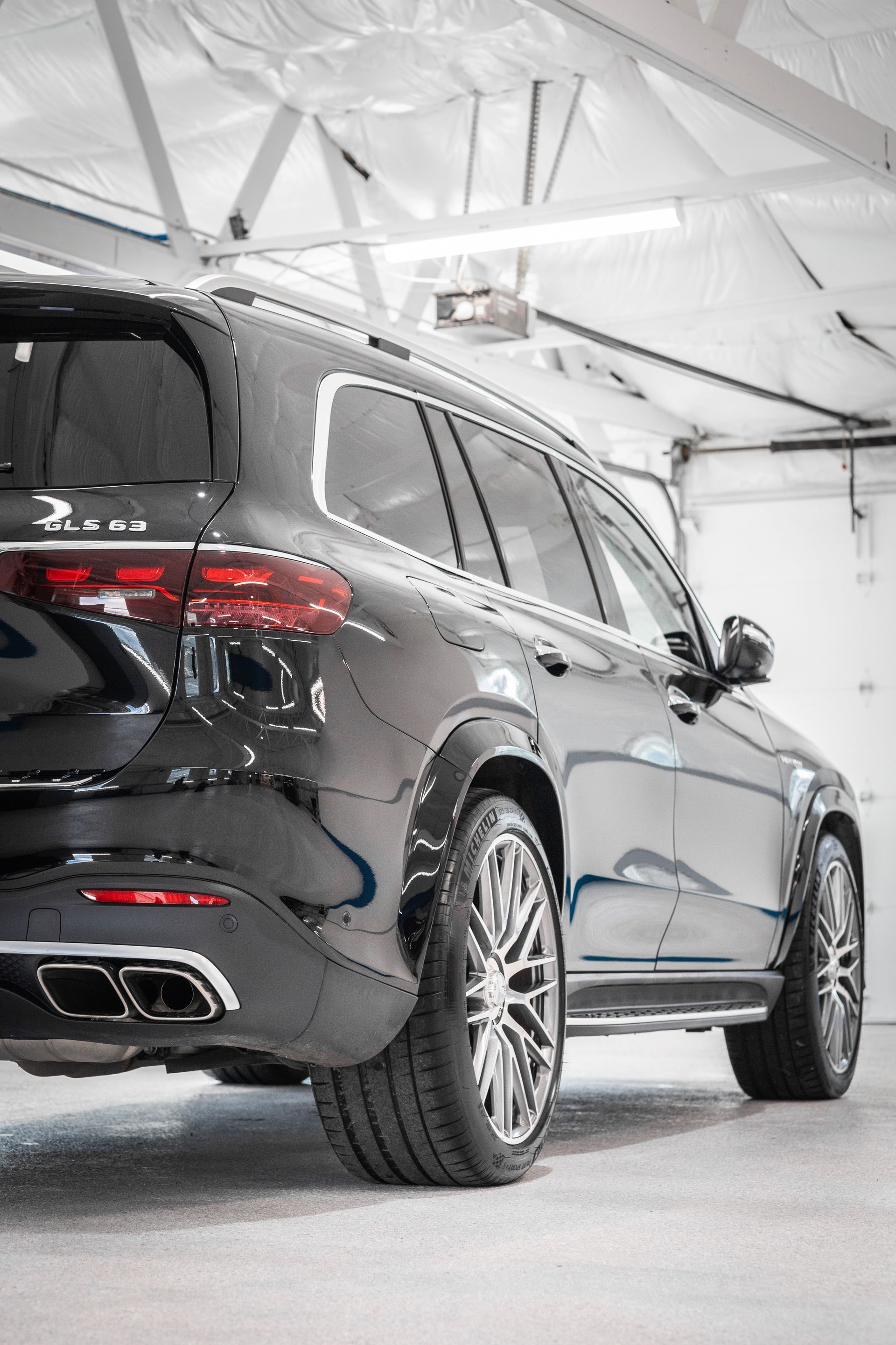 A red jeep with black fender flares is parked in a garage