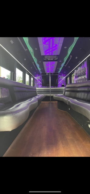 The inside of a limousine with purple lights on the ceiling.