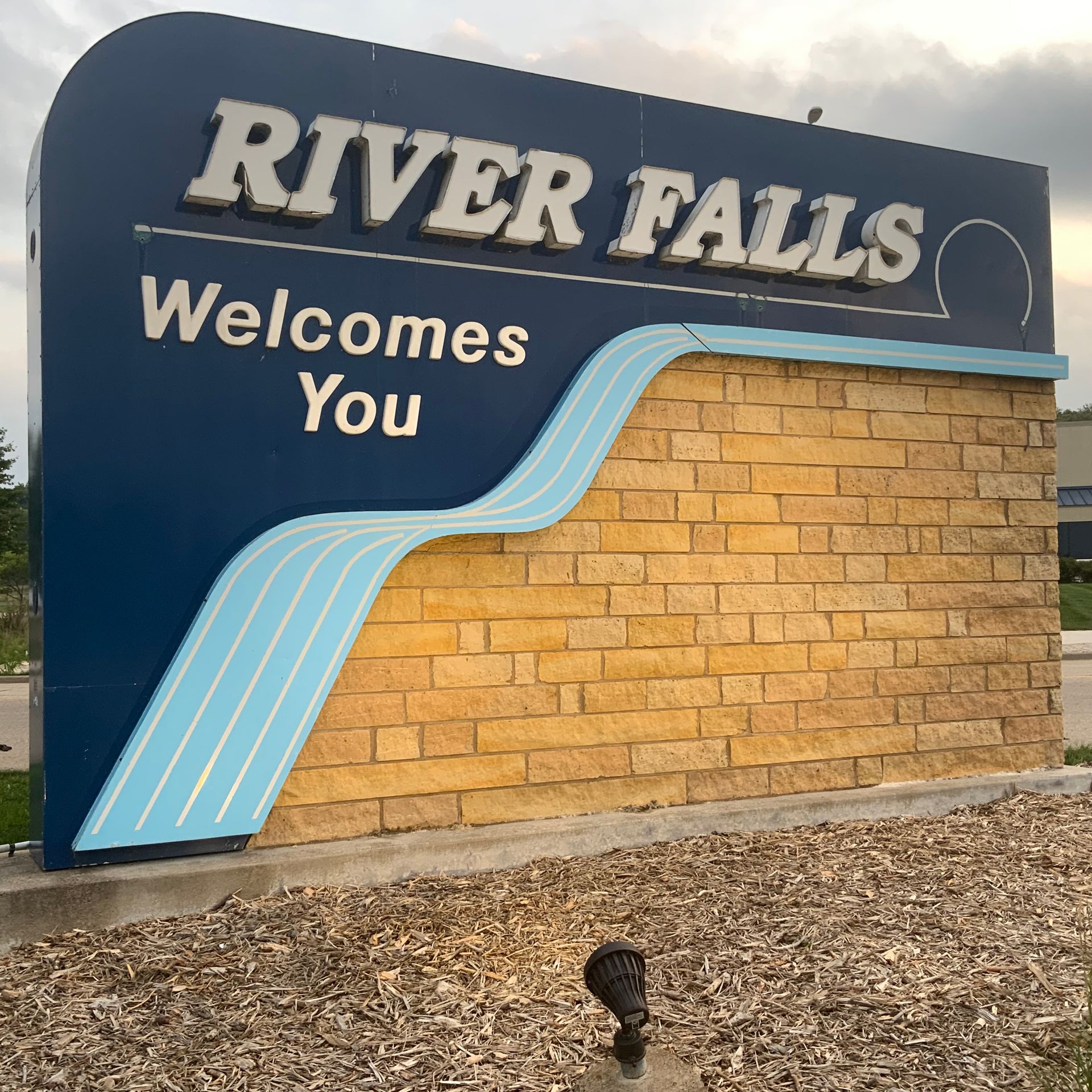 A river falls welcomes you sign on a brick wall