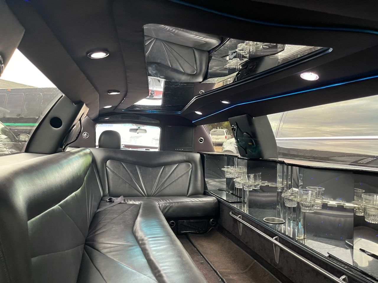 The inside of a limousine with black leather seats and tables.