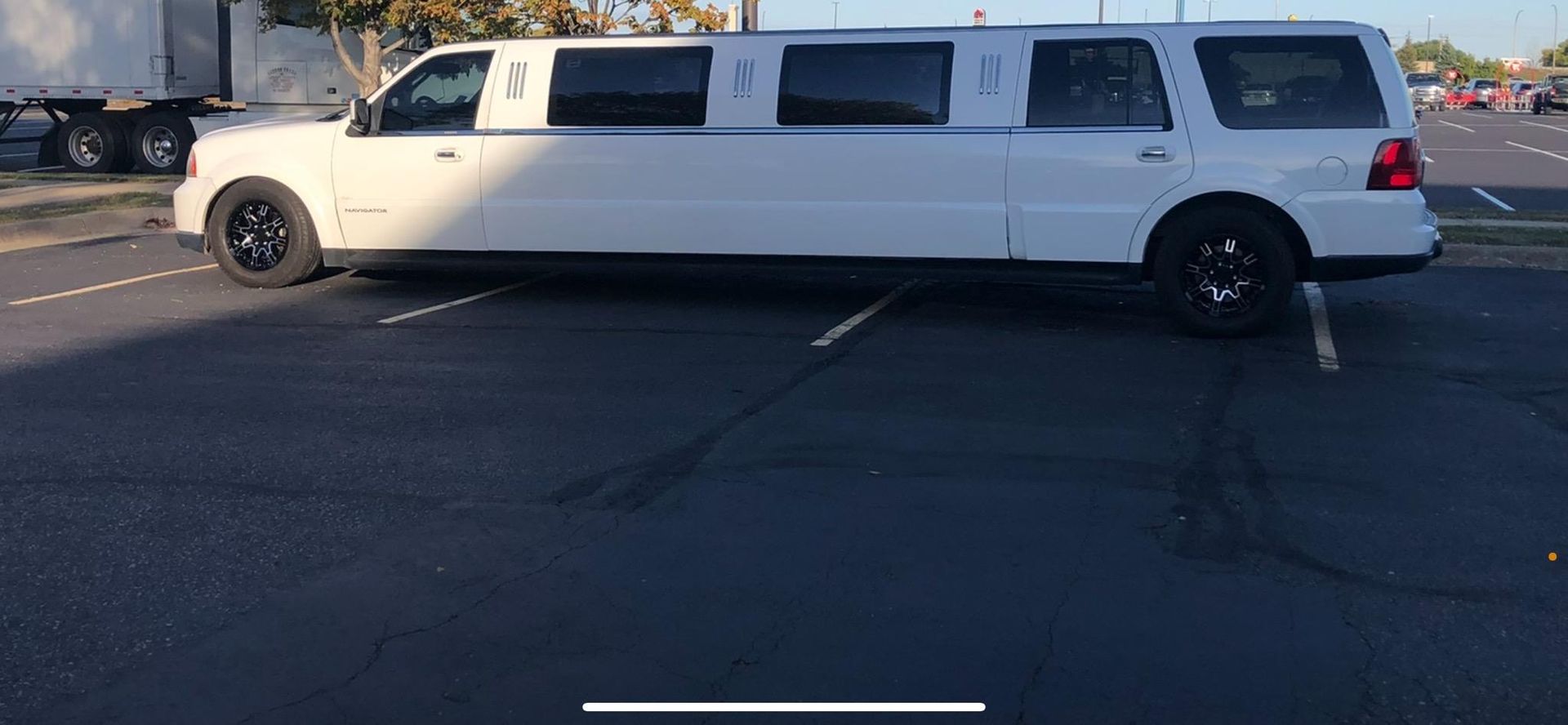 A white limousine is parked in a parking lot.