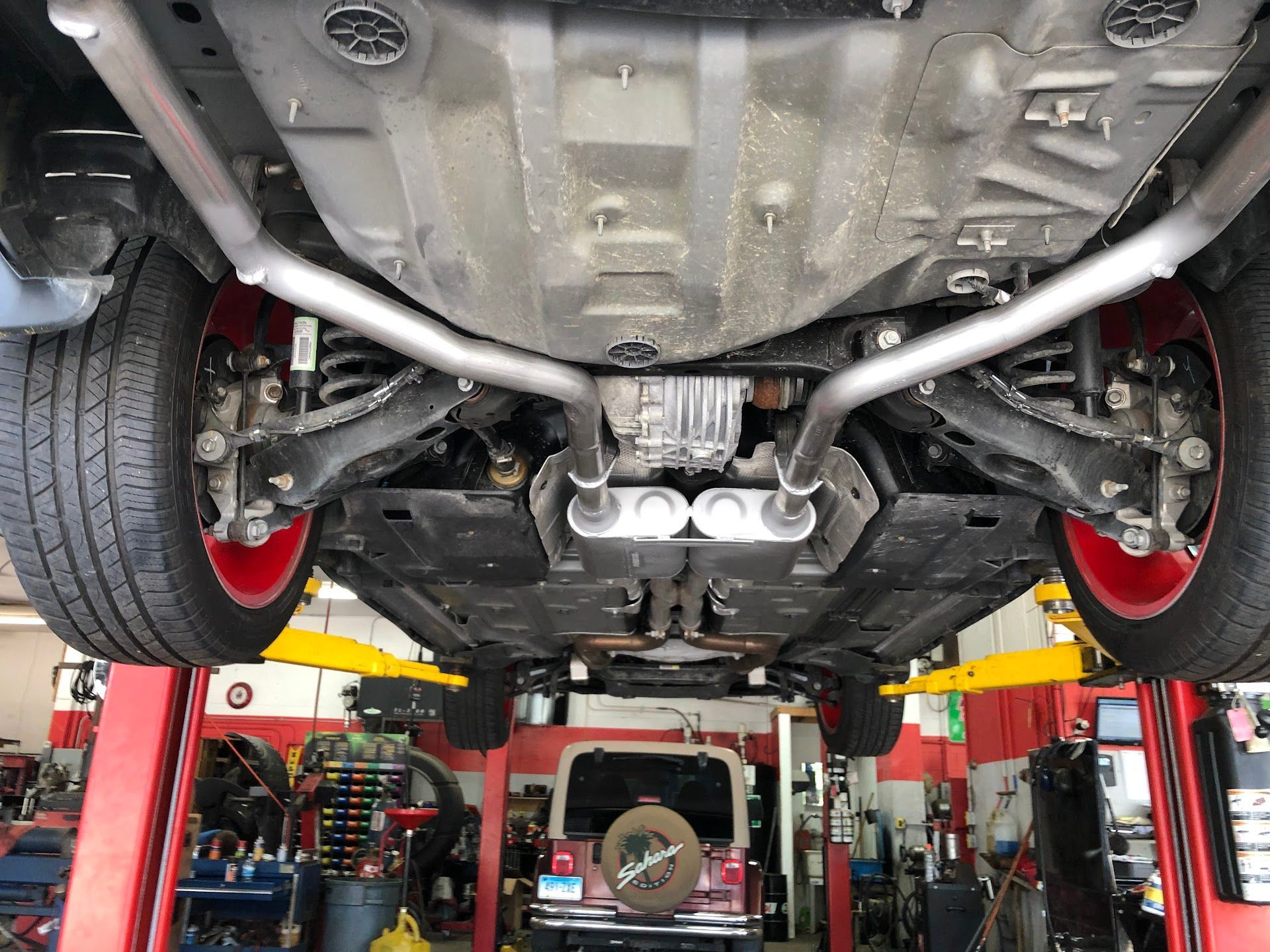 Undercarriage of a vehicle on a lift, with dual exhaust system and red rims. | Rose Brothers Garage