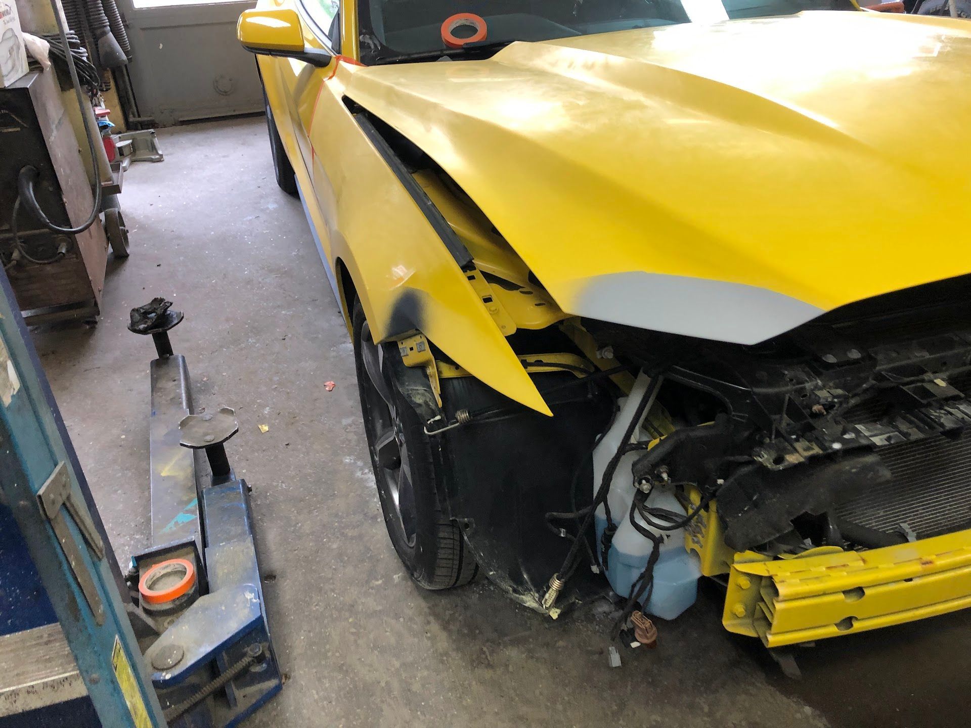 Yellow car with front-end damage in a workshop, the fender is bent. | Rose Brothers Garage
