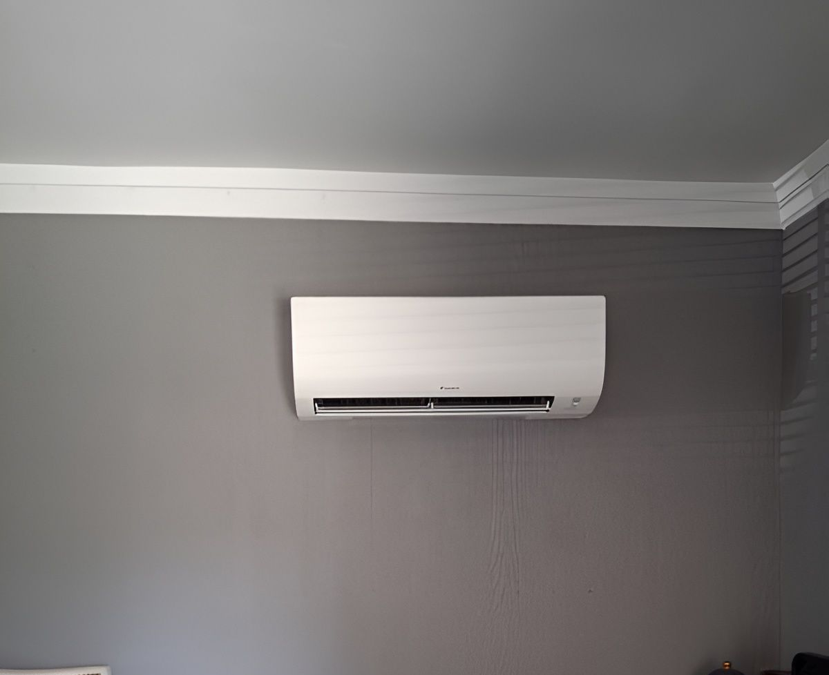 White air conditioning unit on a gray wall under white trim.