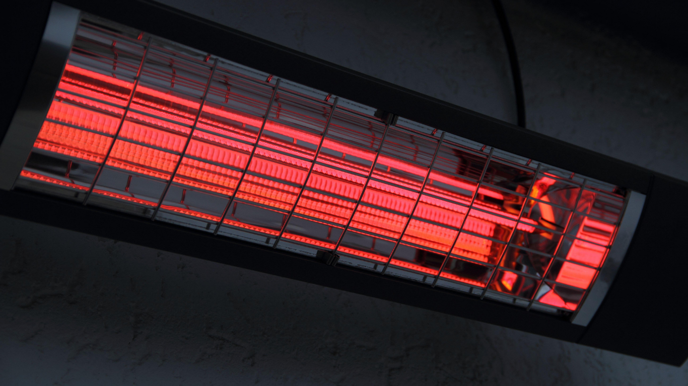 Infrared electric heater, glowing red, mounted on a dark surface.