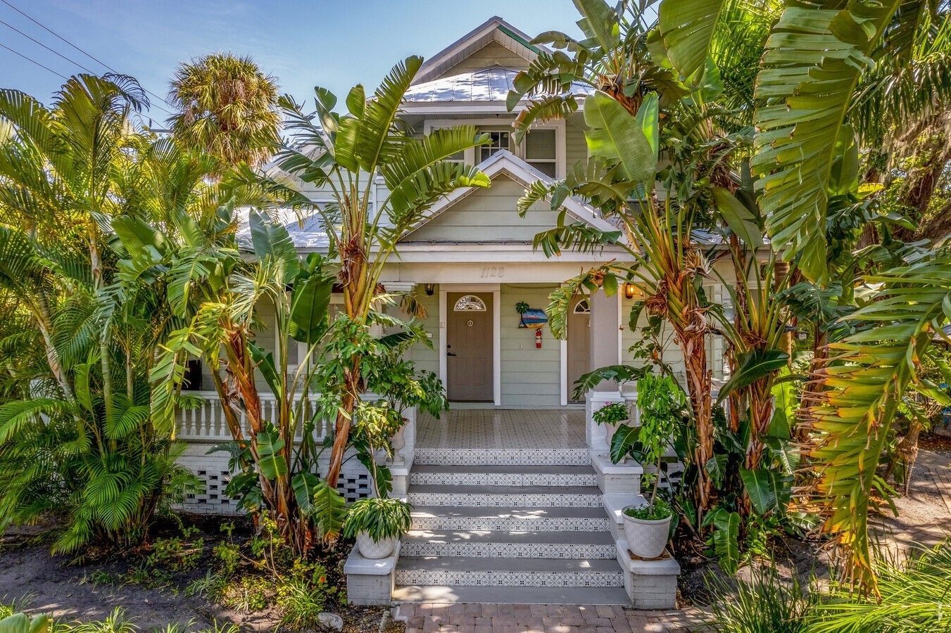 A white house surrounded by trees and bushes on a sunny day.