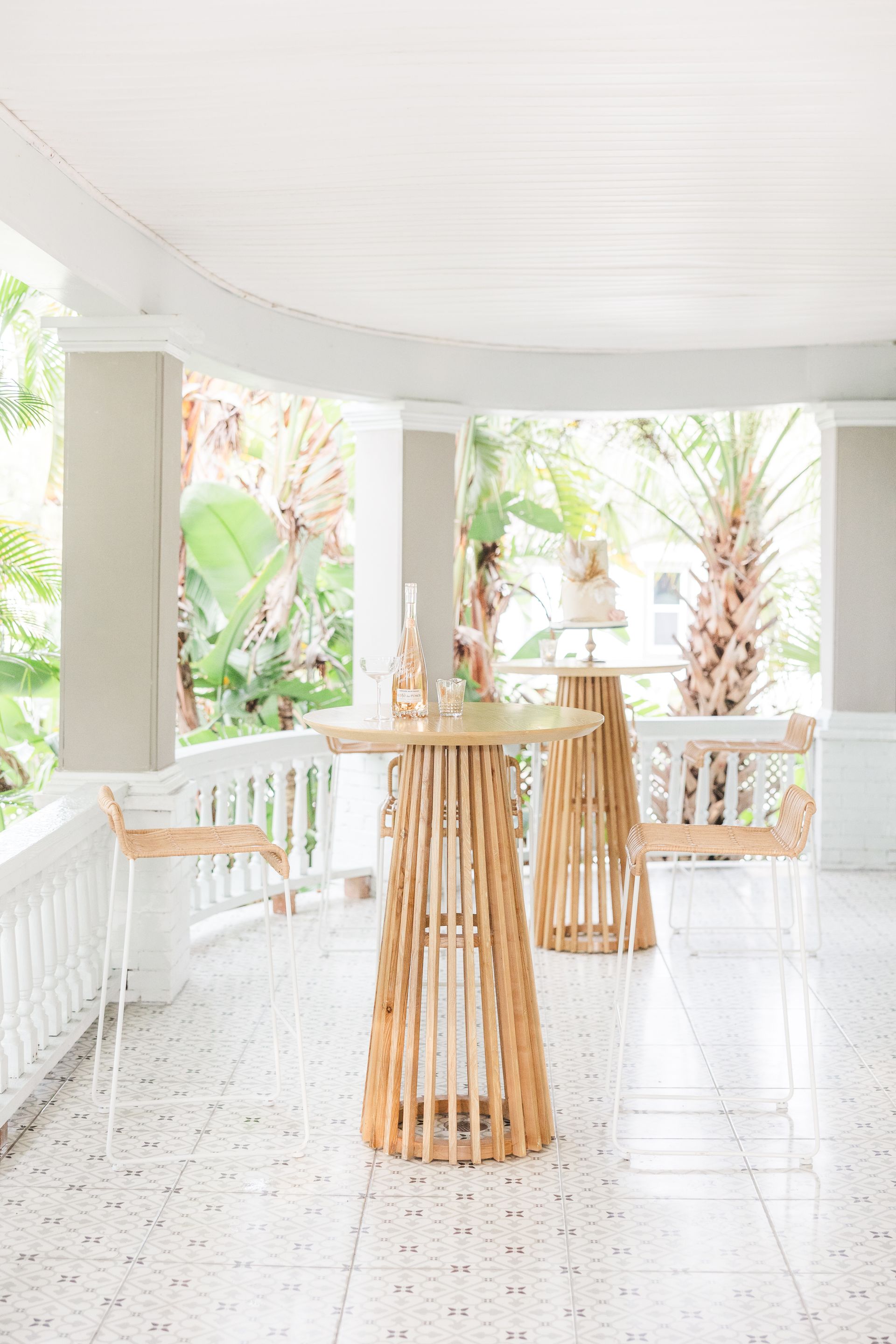 Two wooden tables are sitting on a tiled floor on a porch.
