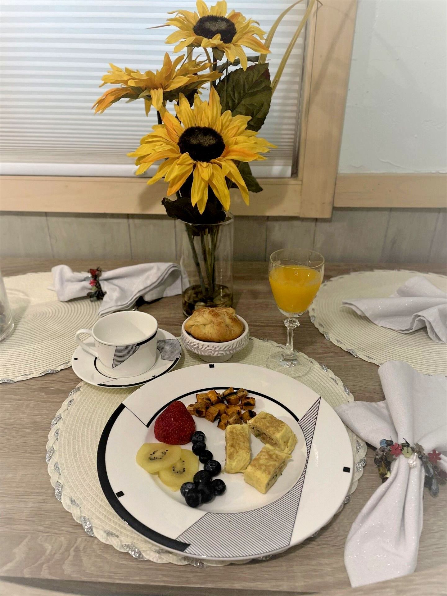 A plate of food is sitting on a table next to a vase of sunflowers.