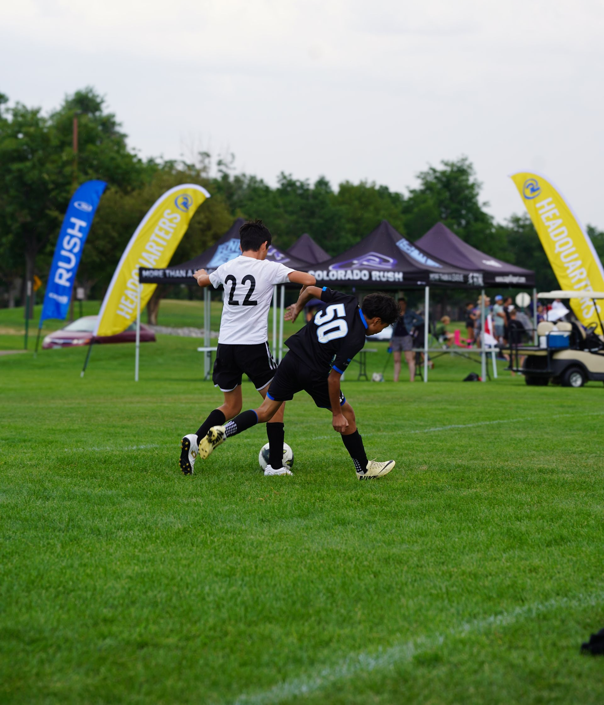 Two soccer players are playing a game of soccer on a field.