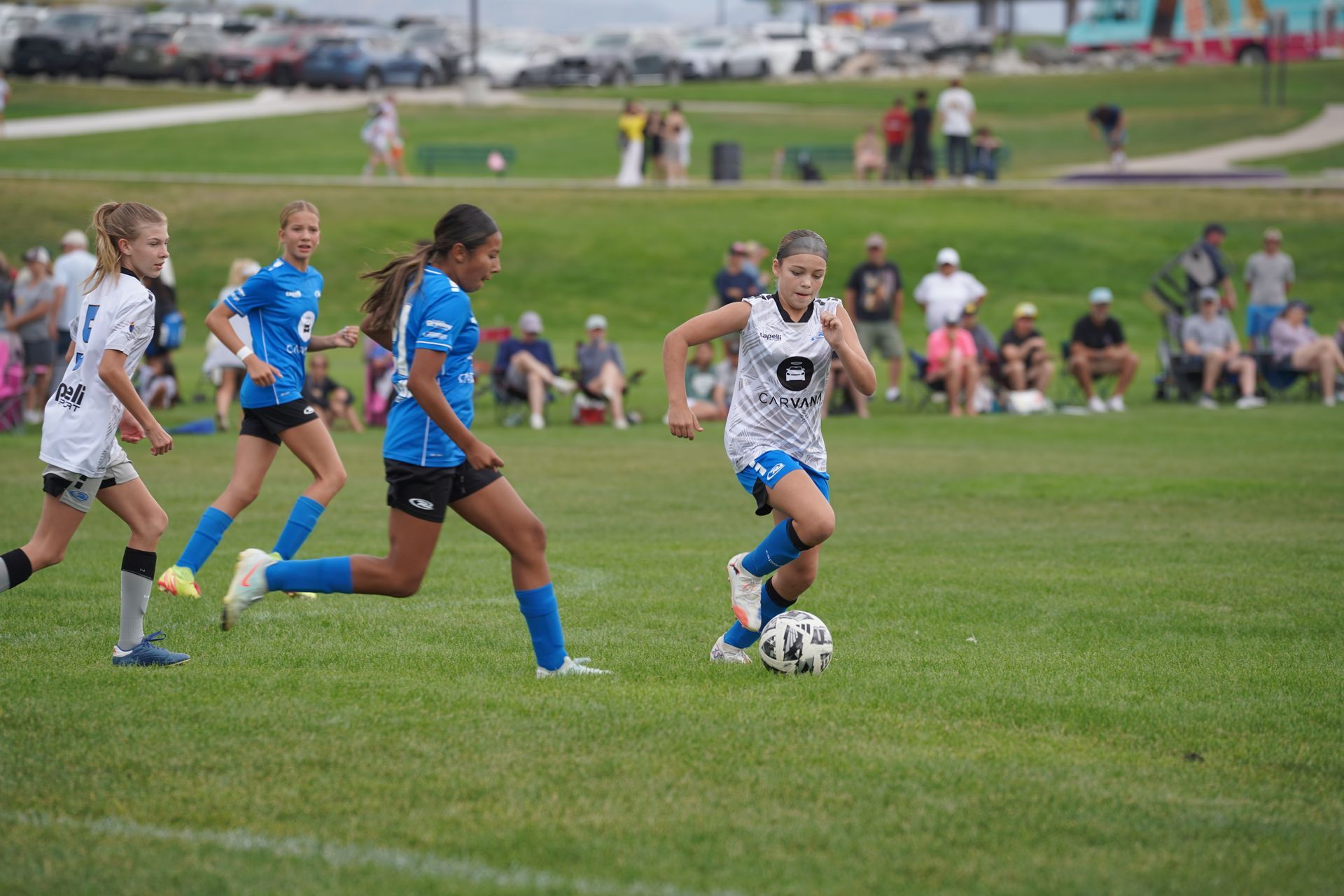 Two young girls are playing soccer on a field.