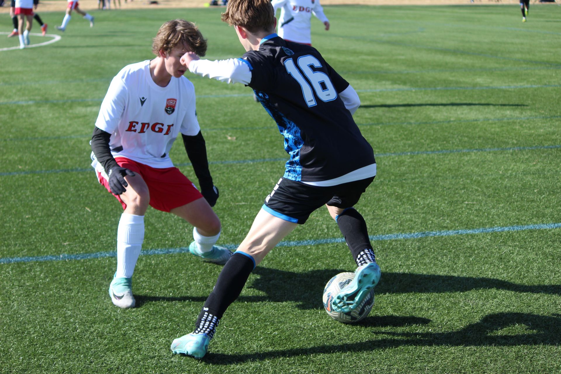 Two soccer players are playing a game of soccer on a field.