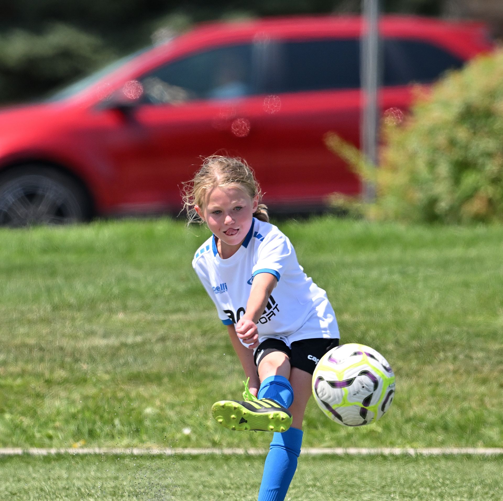 A young girl is kicking a soccer ball on a field