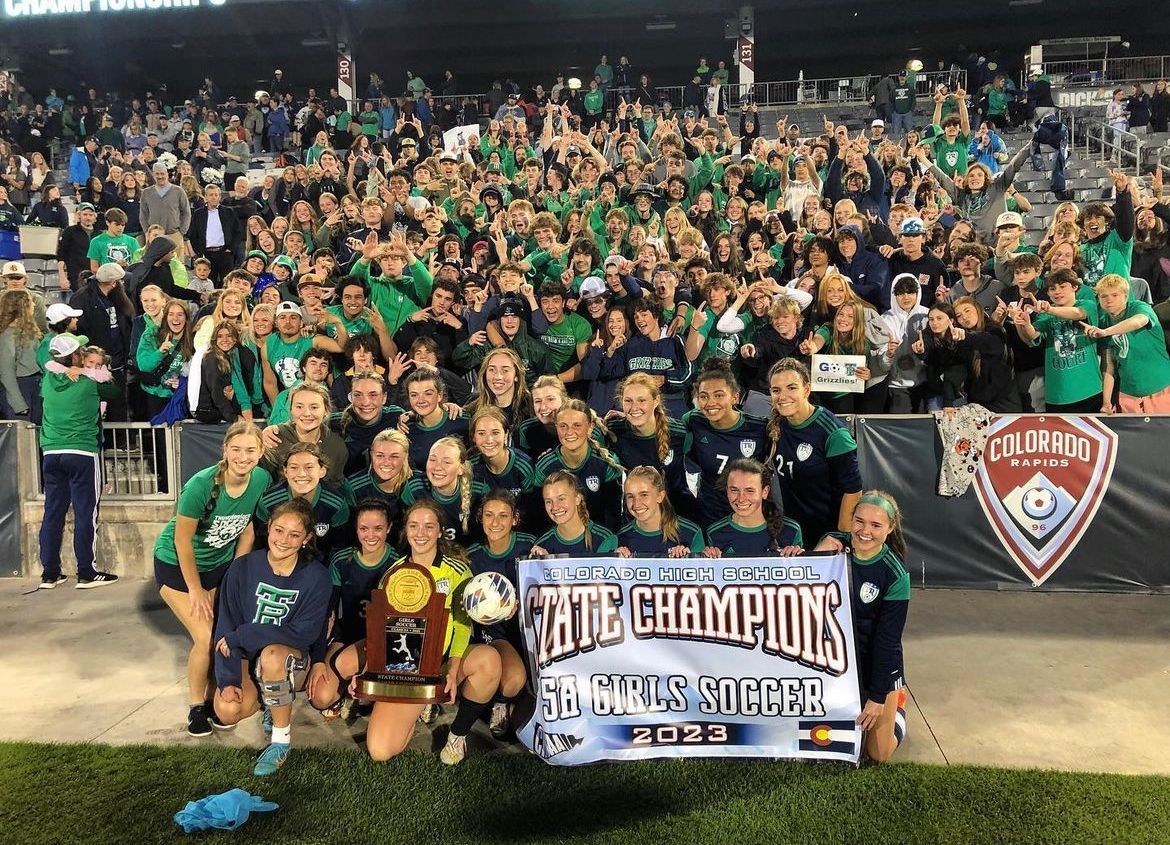 A group of people are posing for a picture on a soccer field.