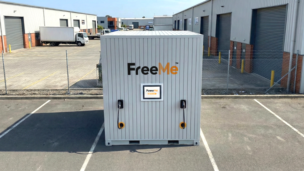 Freestanding groundwork free FreeMe EV Charging container in an industrial parking lot, with white and gray panels.