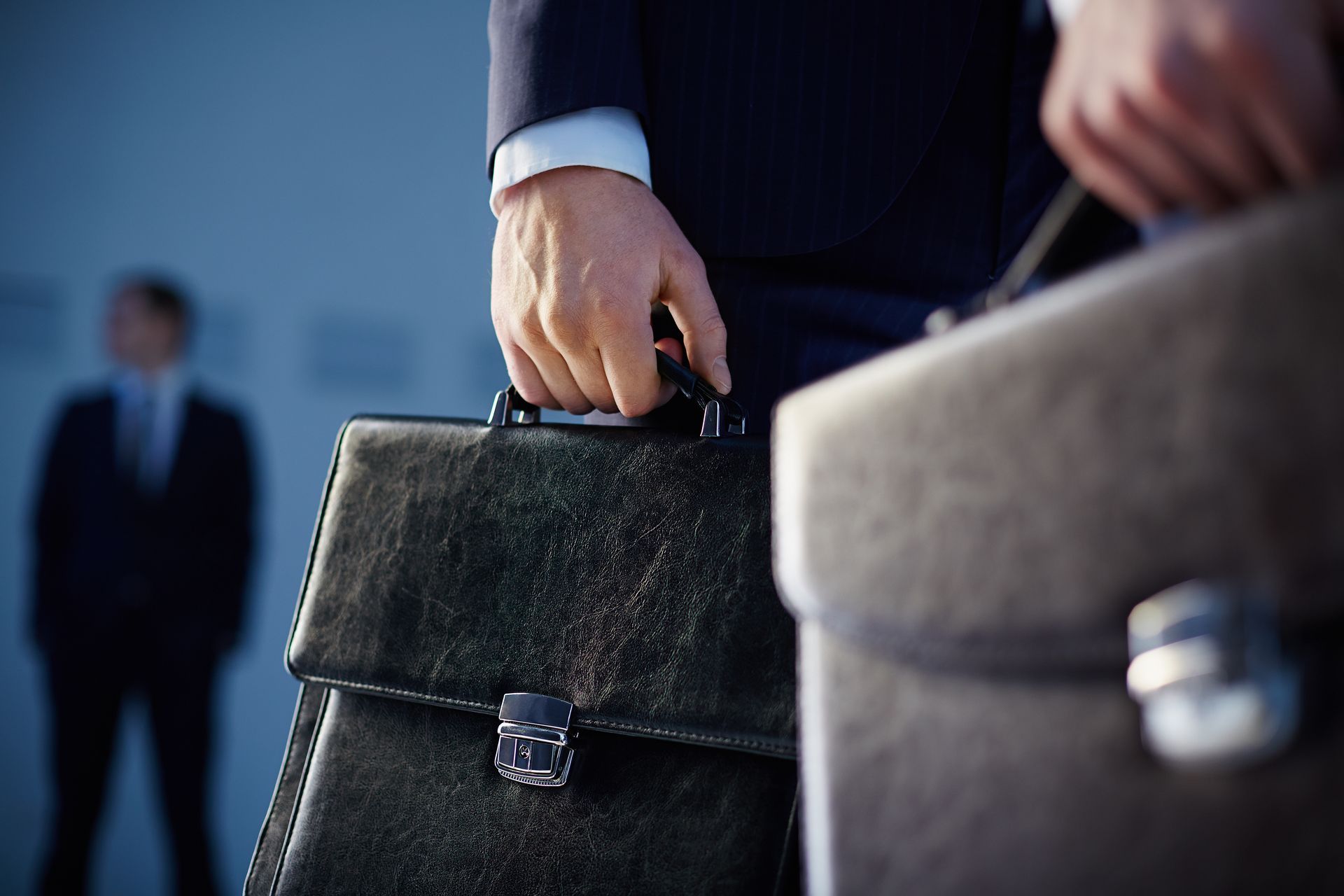 Businessmen, close up view of hands holding briefcases, one in focus, another out of focus.