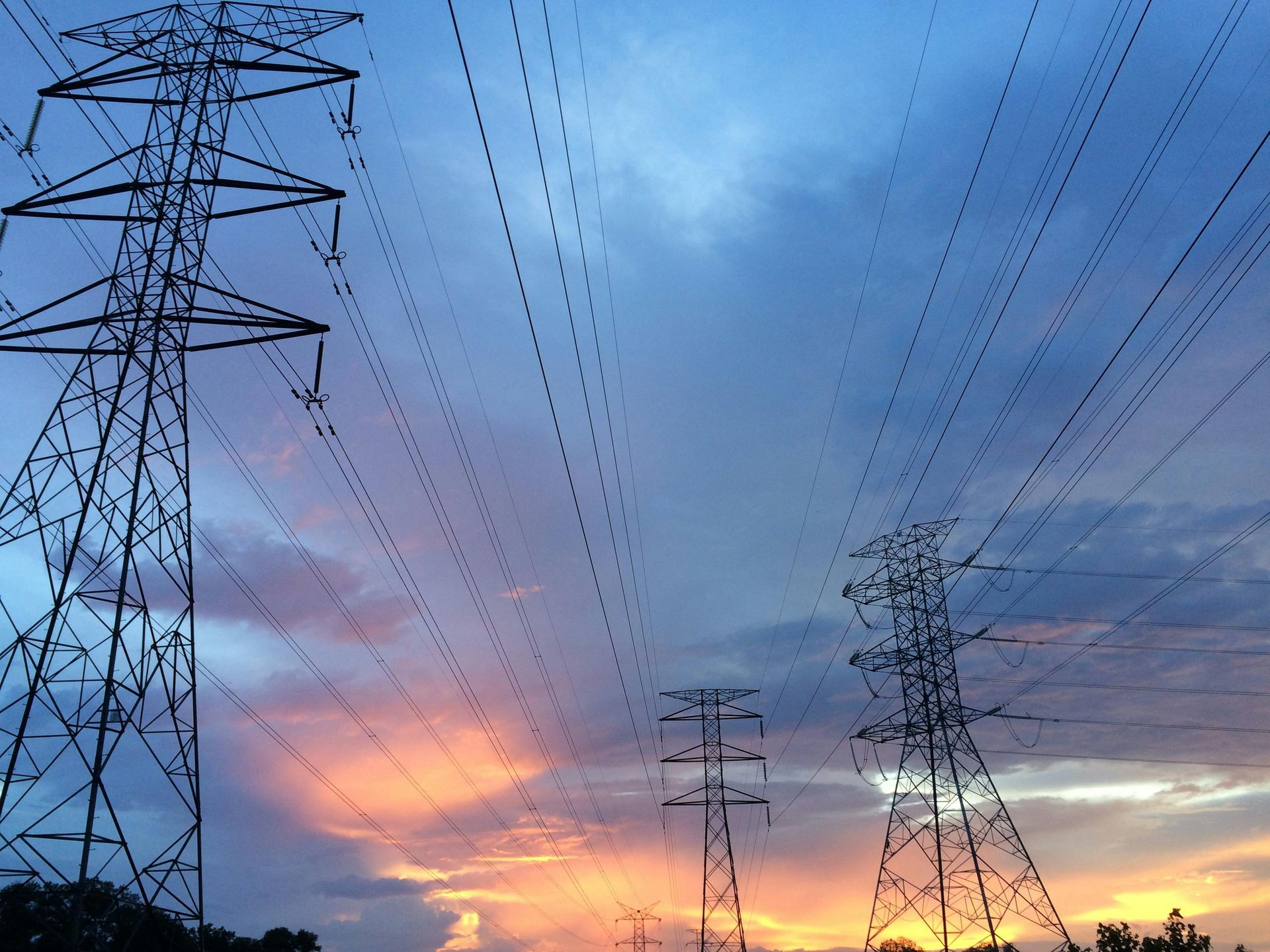 A sunset with a lot of power lines in the foreground