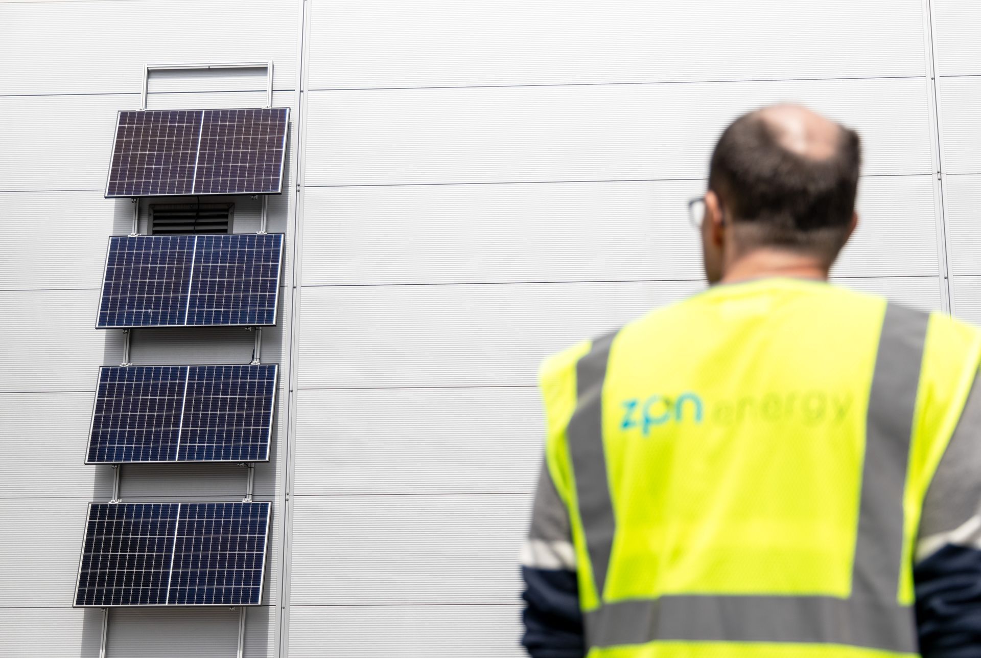 A man wearing a yellow vest that says zpn energy in front of solar panels as part of a PPA