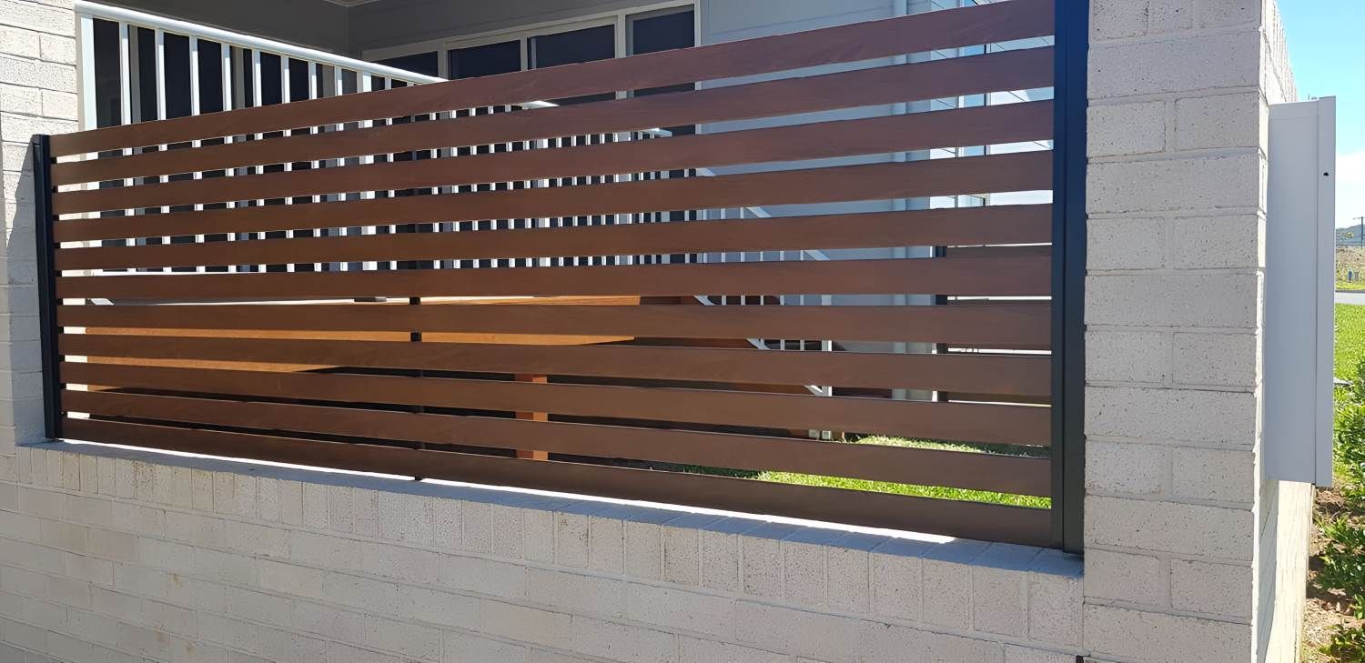 A Wooden Fence Is Sitting On Top Of A White Brick Wall — Metal Fencing Supplies in Taree, NSW