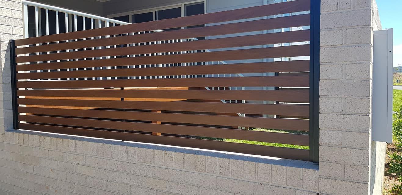 A wooden gate is sitting on top of a white brick wall — Metal Fencing Supplies in Taree, NSW
