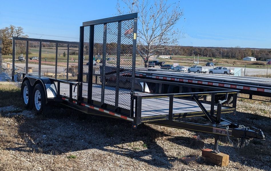 Black utility trailer with metal mesh sides, parked outdoors on a sunny day.