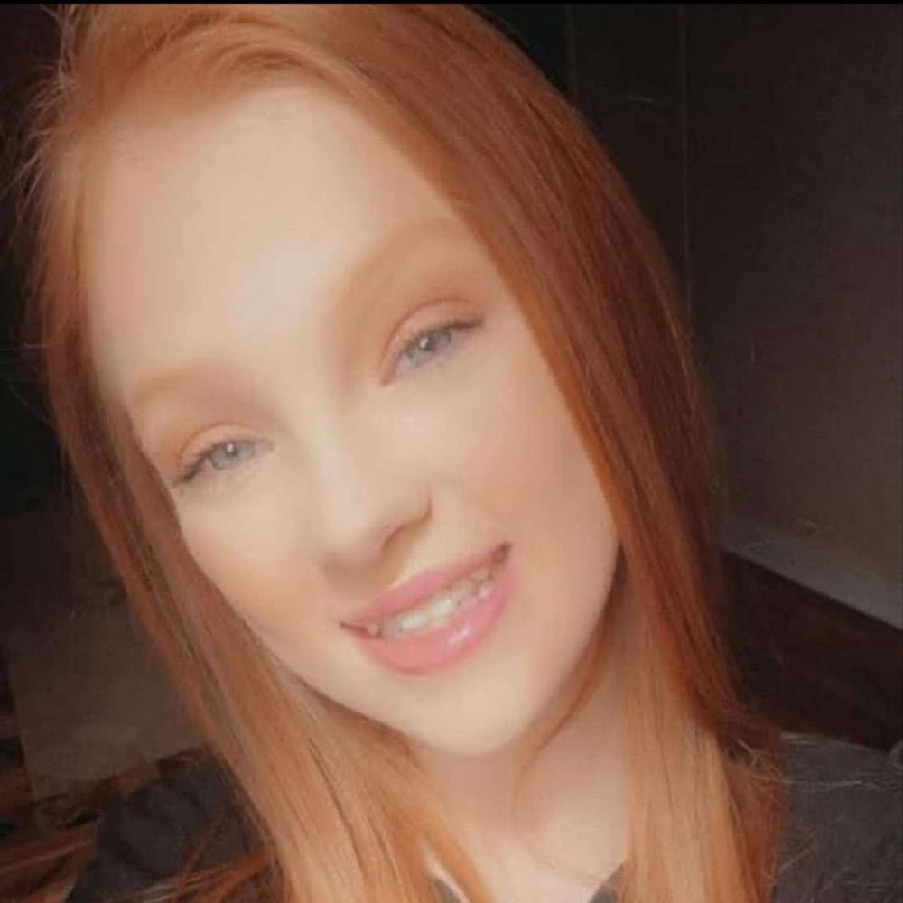 A close up of a woman 's face with red hair and blue eyes.