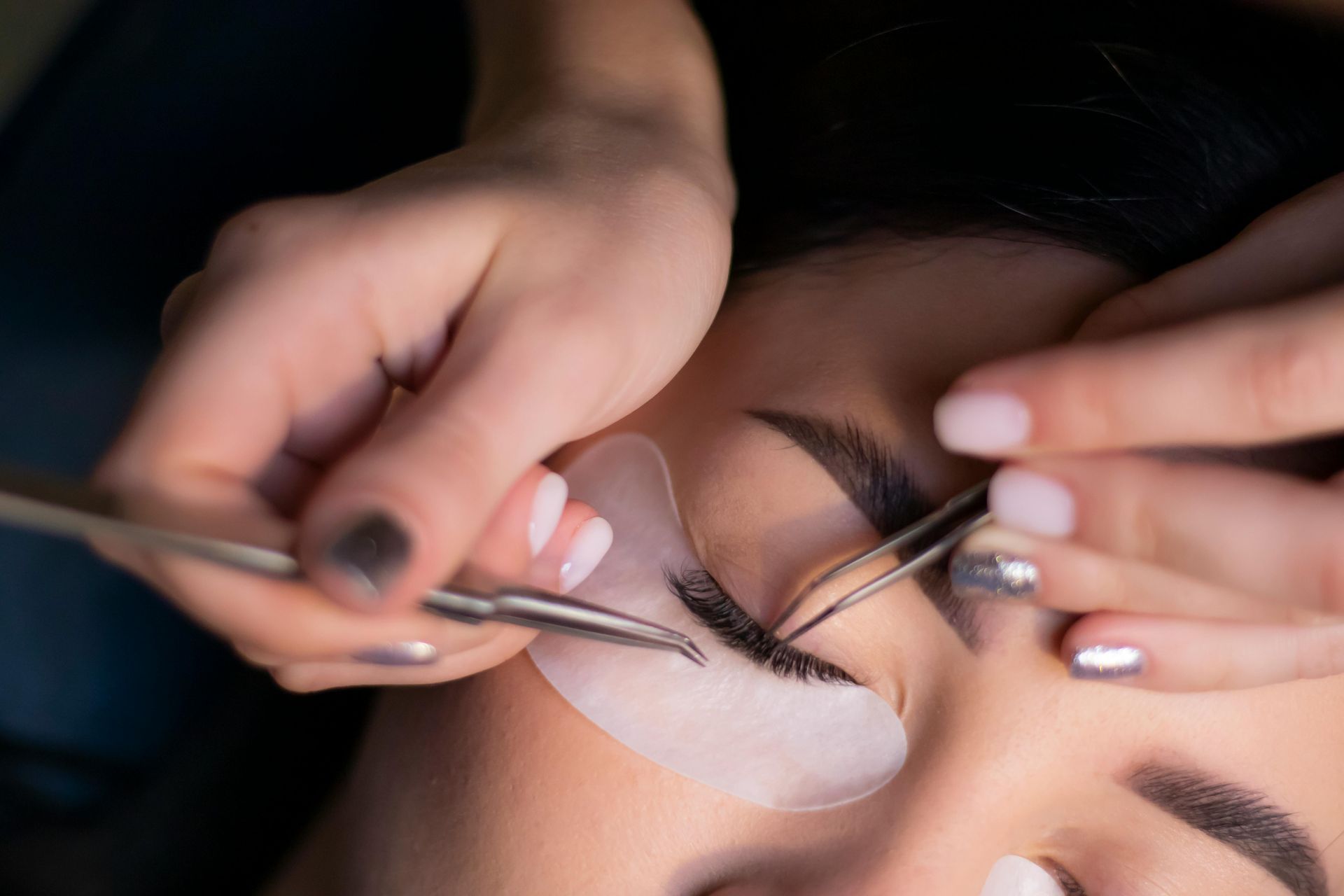 A woman is getting her eyelashes done by a makeup artist.