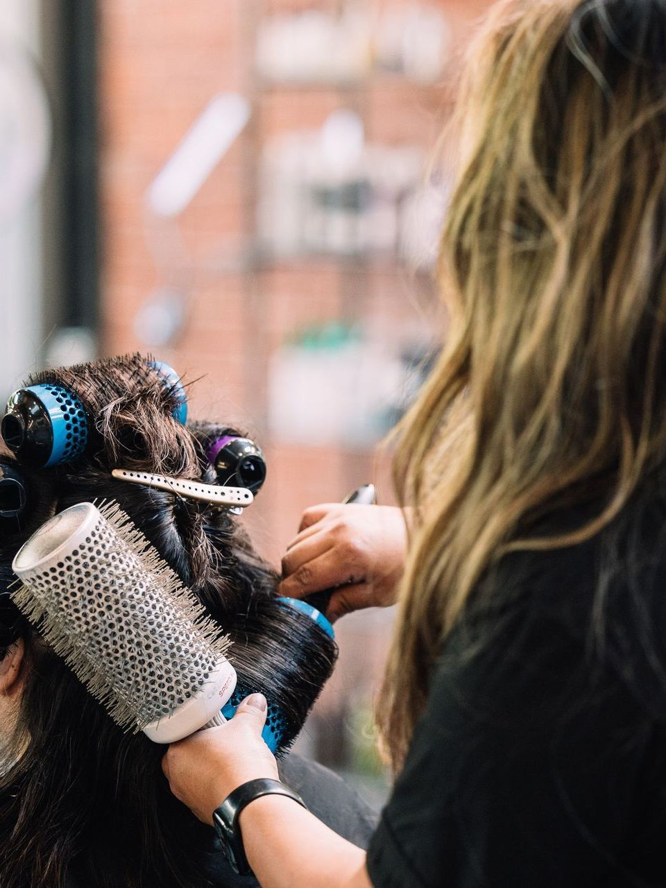 Esmeralda styling a client's hair with rollers