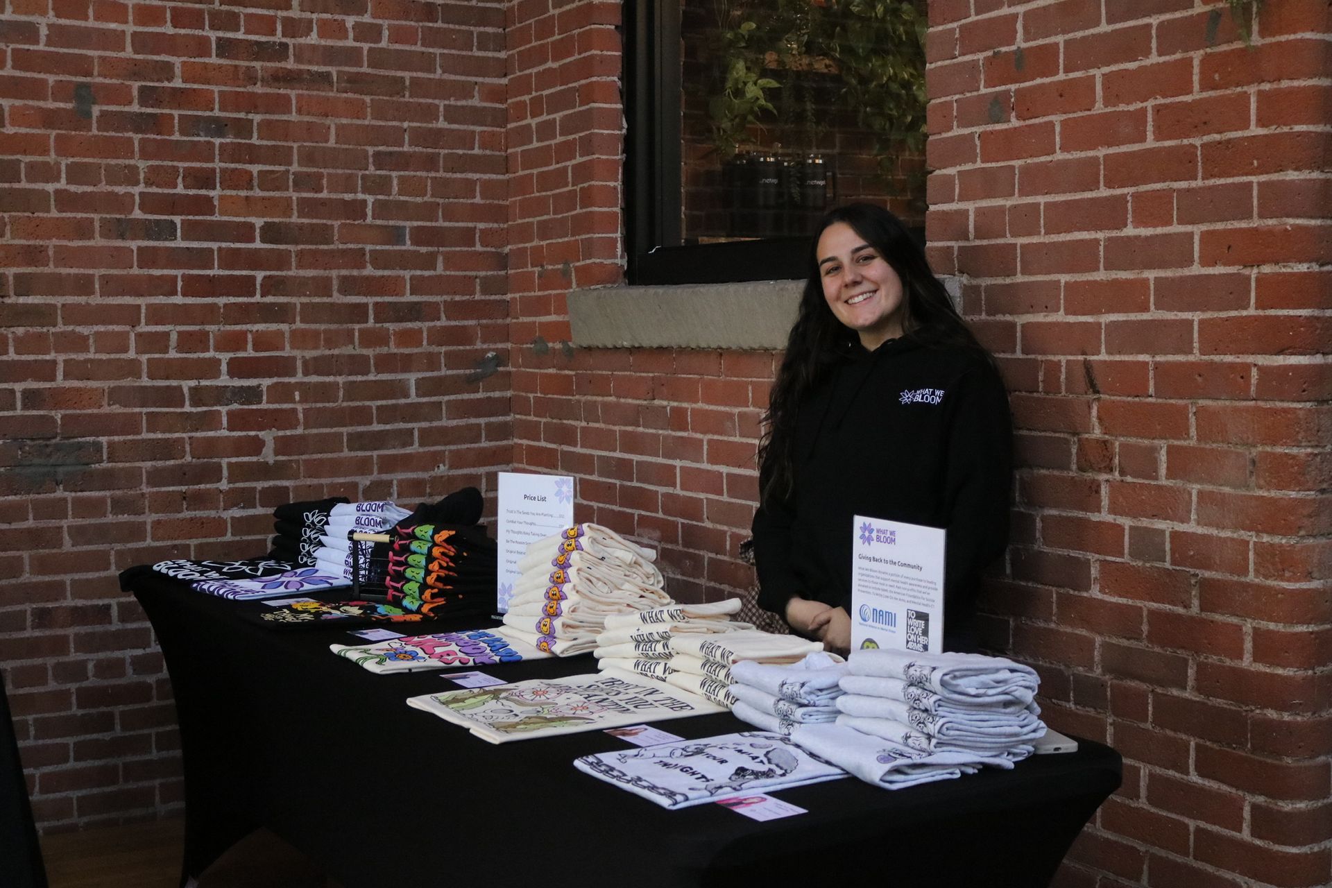 A woman is sitting at a table in front of a brick wall