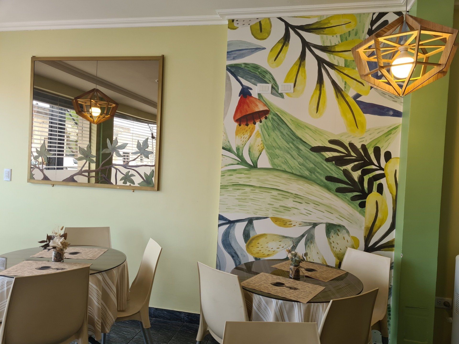 Interior de cafetería: mesas con manteles color canela y sillas blancas.