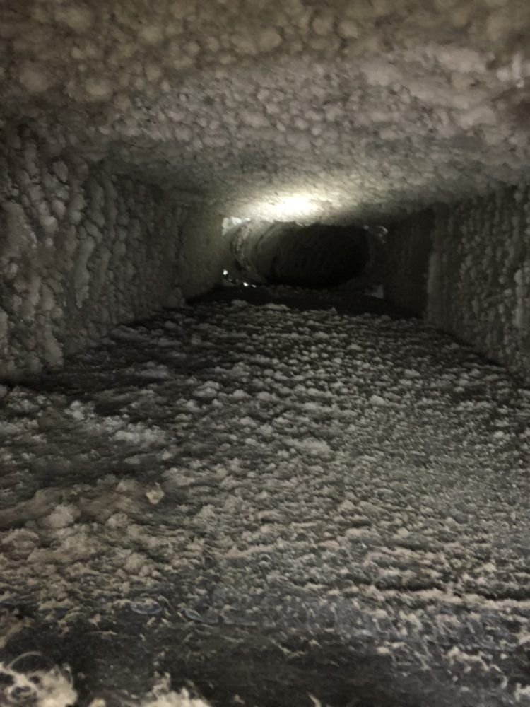 Inside of an air duct, covered in thick dust and debris, illuminated by a light in the distance.