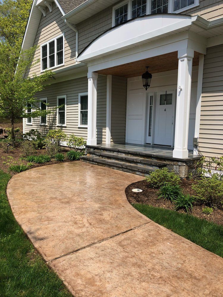 Beige house with porch, walkway and landscaping.