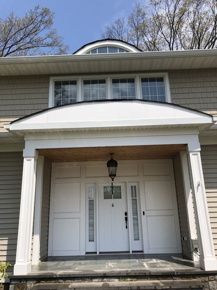 Beige house front with white door, columns, and windows; porch with dark stone steps.